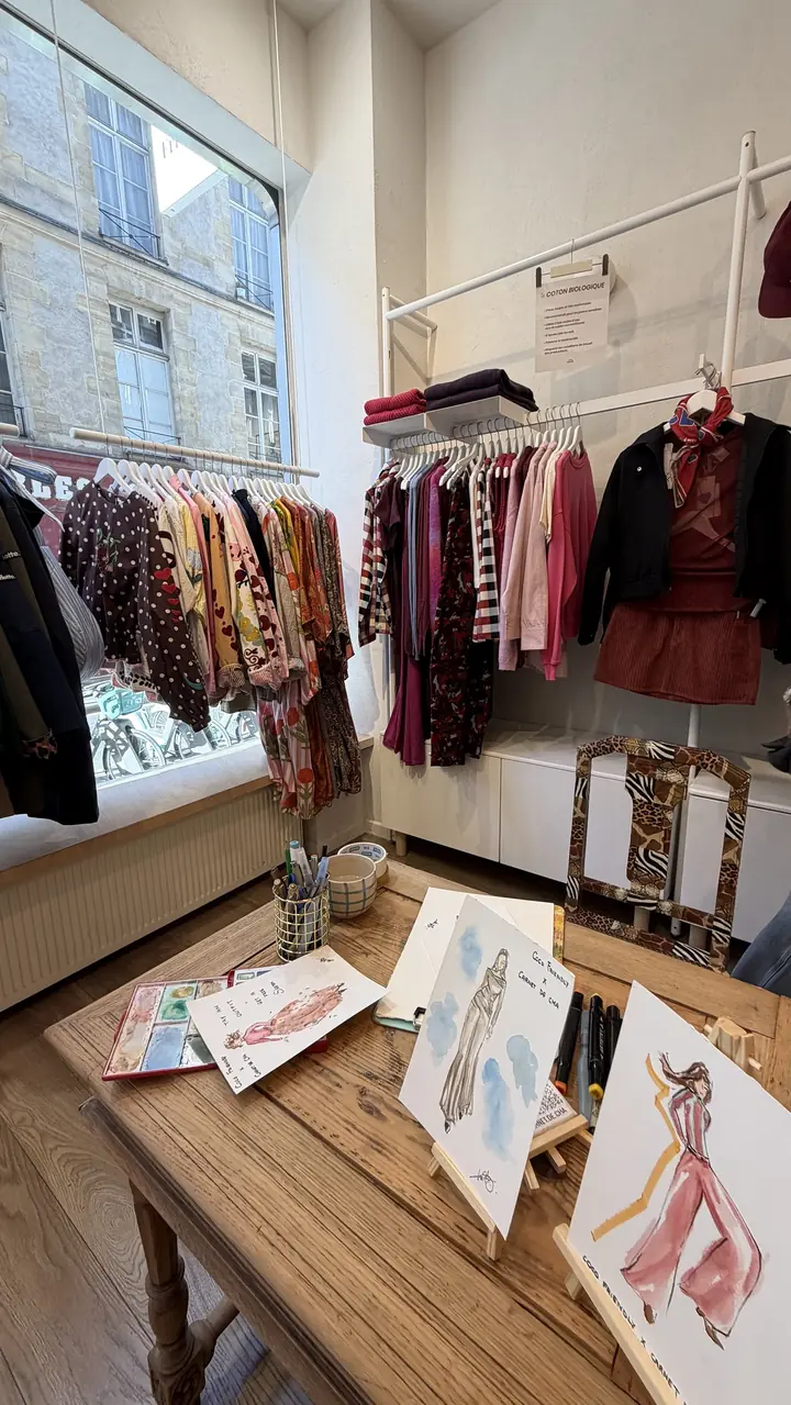 Table d'illustratrice live installée dans une boutique de mode du Marais, entre les portants