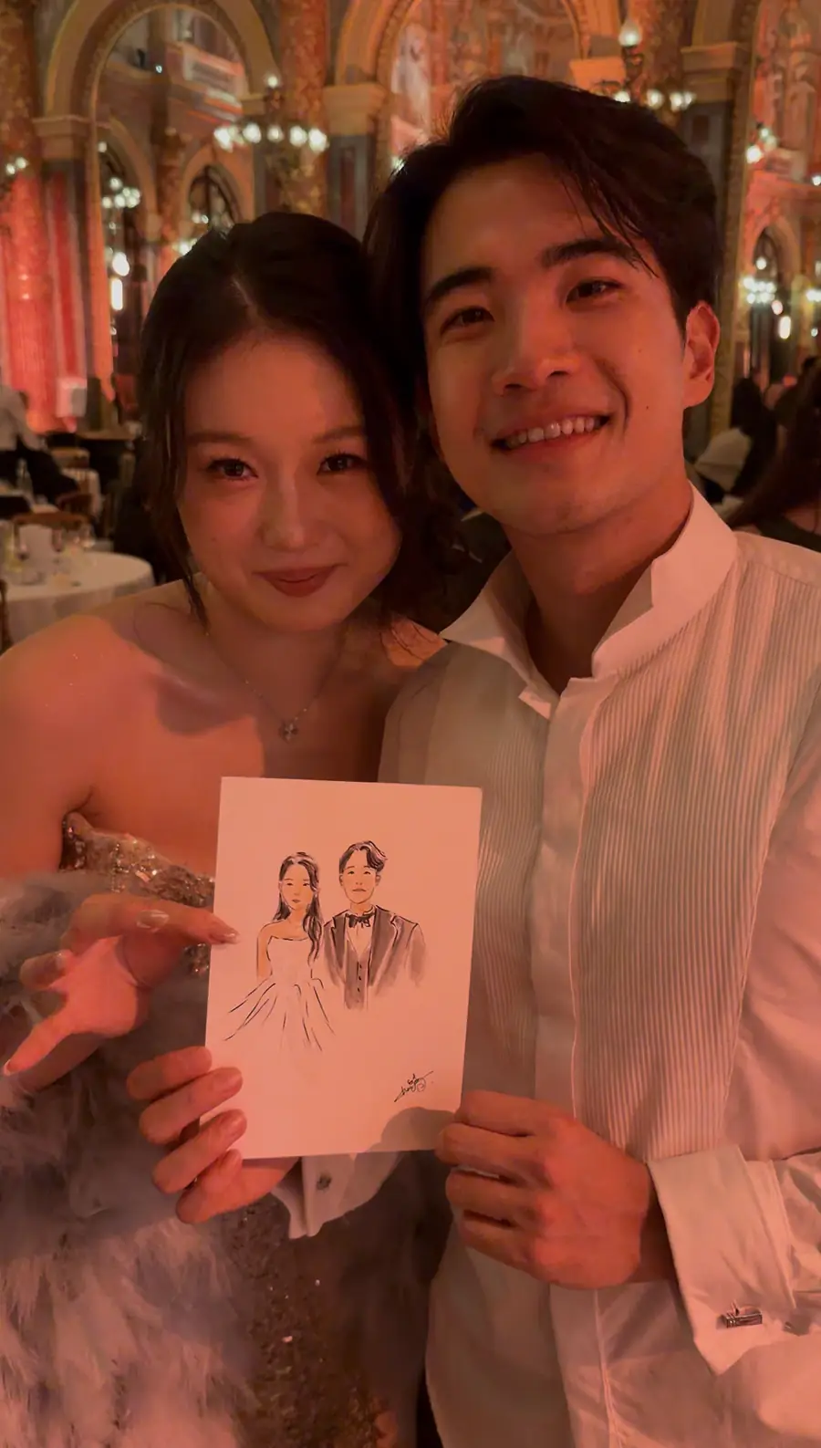 Couple holding their ink portrait in the grand reception hall