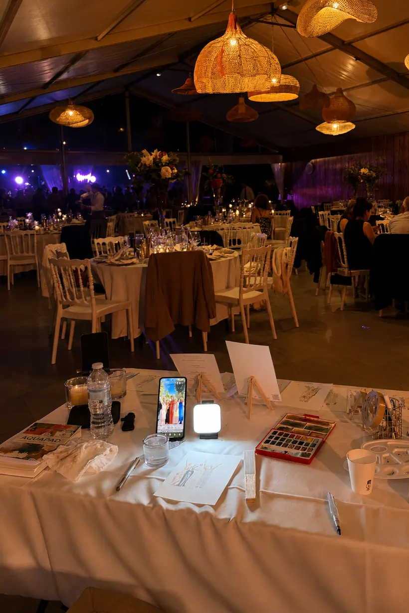 Poste de l'illustratrice live installé dans une salle de réception de mariage, le soir